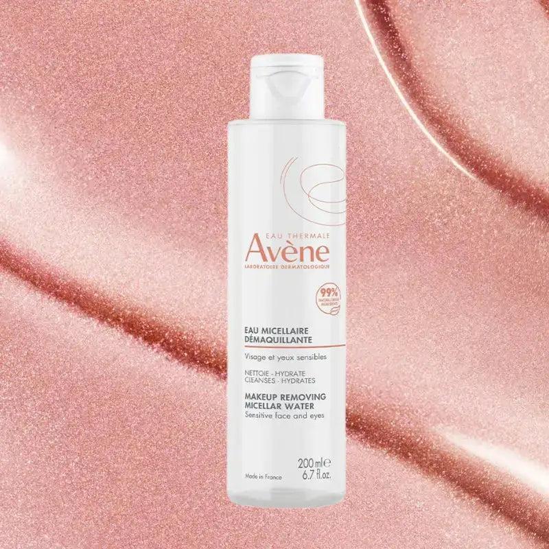 A bottle of Avene Make-up Removing Micellar Water stands centered against a sparkling rose gold glitter background.