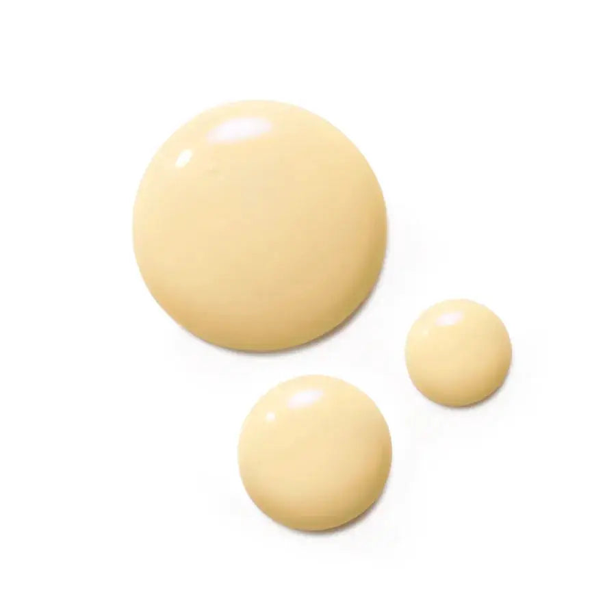Three smooth, glossy beige cosmetic droplets of varying sizes on a solid white background.