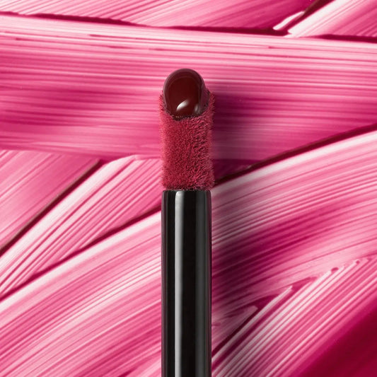 Lip brush with red bristle tip on a pink textured background
