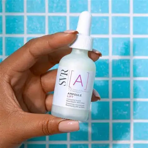 Hand holding a skincare serum bottle with a blue tiled background
