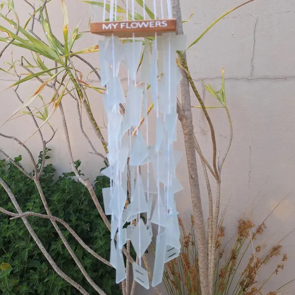 Decorative wind chime with 'MY FLOWERS' sign against a natural background