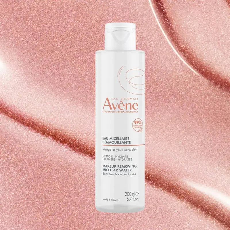 A bottle of Avene Make-up Removing Micellar Water stands centered against a sparkling rose gold glitter background.