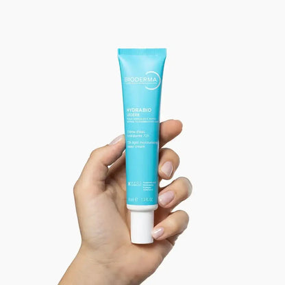 Hand holding a Bioderma Hydrabio tube against a white background