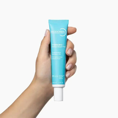 Hand holding a Bioderma Hydrabio tube against a white background