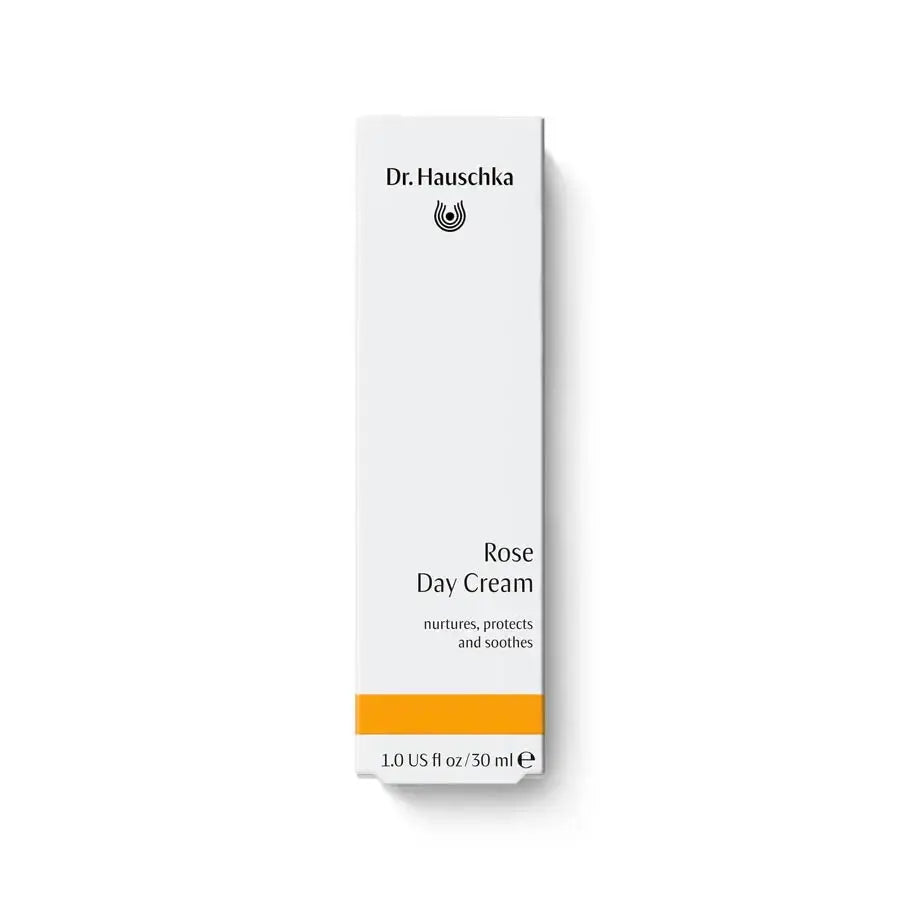 A tall, narrow white box for Dr. Hauschka Rose Day Cream, featuring black text and a bright orange band near the bottom, set against a clean white background.