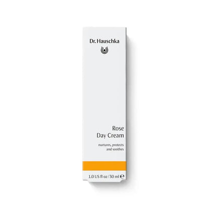A tall, narrow white box for Dr. Hauschka Rose Day Cream, featuring black text and a bright orange band near the bottom, set against a clean white background.