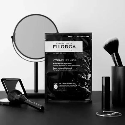 Filorga Hydra-Filler Mask packaging on a table with makeup tools.