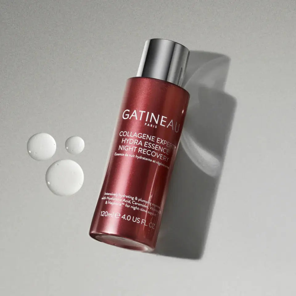 A bottle of Gatineau Paris Collagen Express Night Recovery Hydra Essence, shown at an angle on a textured gray background with three clear liquid droplets on the left.