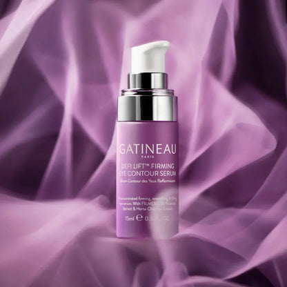 Gatineau Paris Def Lift Firming Die Contour Serum in a lavender purple pump bottle with a white pump and silver collar, set against a draped purple fabric background.