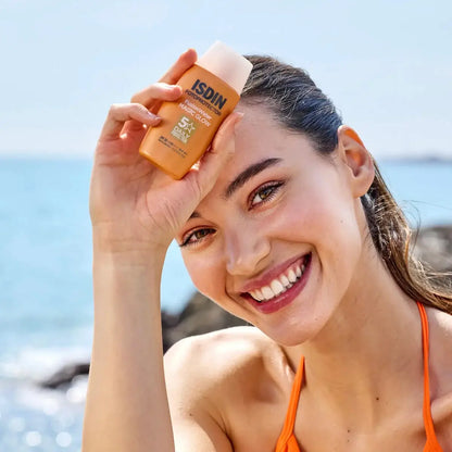 Woman applying ISDIN sunscreen at the beach