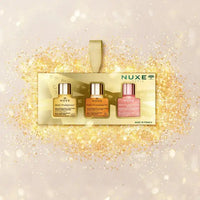 Load image into Gallery viewer, Nuxe nail care set with three bottles on a glittery background
