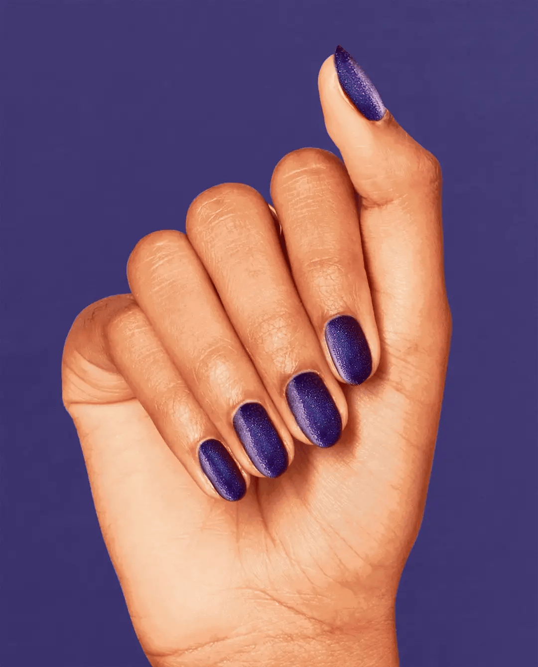 Hand with purple nail polish against a blue background