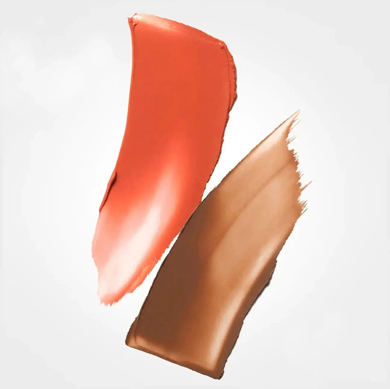 Two cosmetic cream swatches on a light gray background, one in a warm coral-peach shade and the other in a medium tan-brown shade.