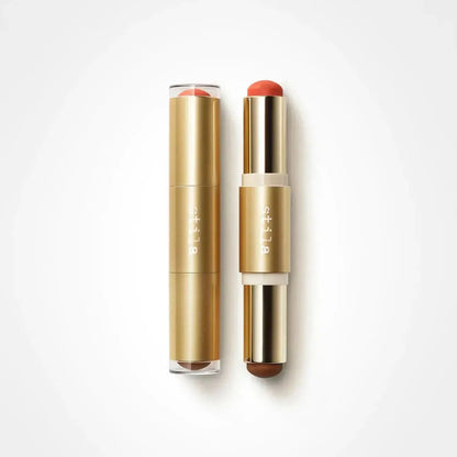 Two gold cosmetic tubes with clear caps, one closed and one open showing a coral-red stick and a brown stick, on a white background. The brand name 'dli la' is printed vertically on the tubes.
