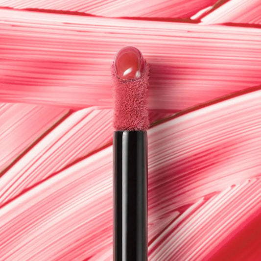 Lip gloss applicator with pink lip gloss on a pink textured background