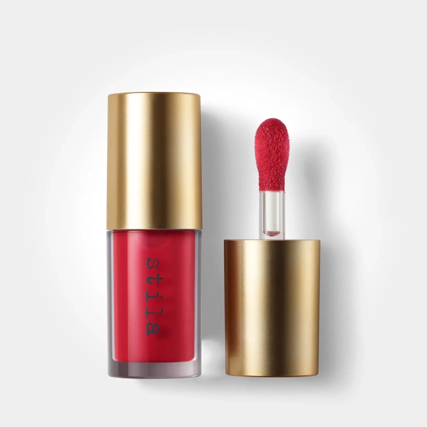 Red lipstick with gold cap and applicator on a white background
