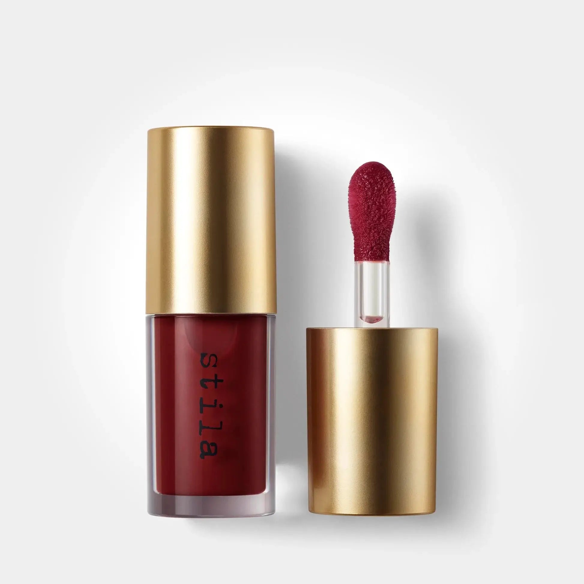 Stila lip gloss with gold cap and red applicator on a white background