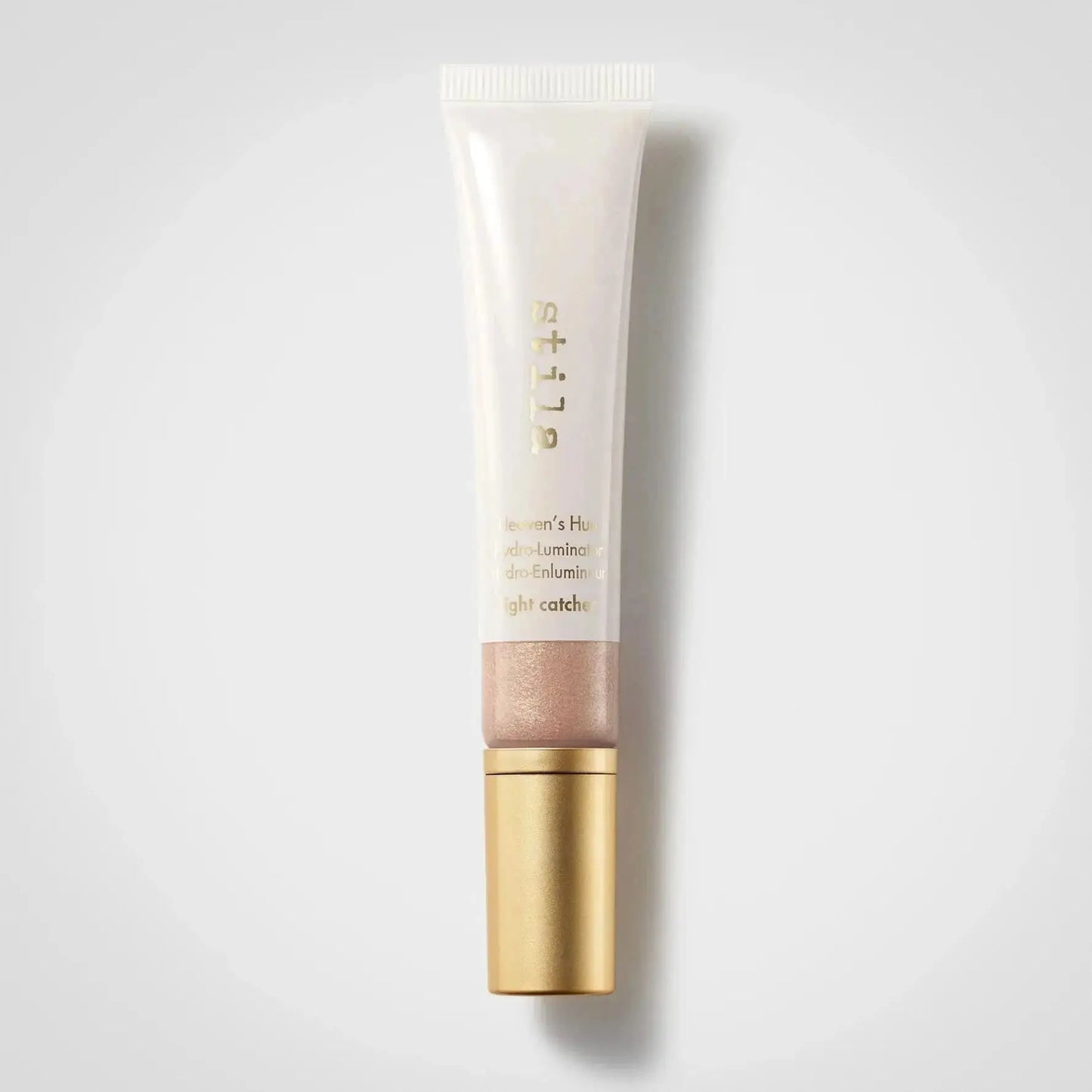 A squeeze tube of Estée Lauder luminous highlighter in 'Luminier's Highlight' with a gold cap, shown on a light gray background with a soft shadow.